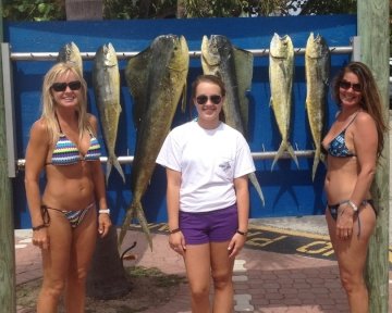 Three women in front of the sailfish marina sign